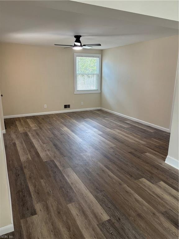 spare room with visible vents, baseboards, dark wood-type flooring, and ceiling fan