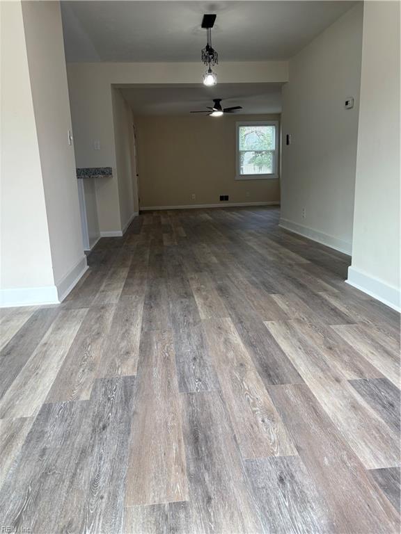 unfurnished living room with baseboards, wood finished floors, and a ceiling fan