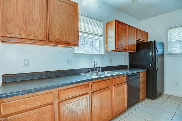 kitchen featuring dark countertops, light tile patterned floors, brown cabinets, black appliances, and a sink