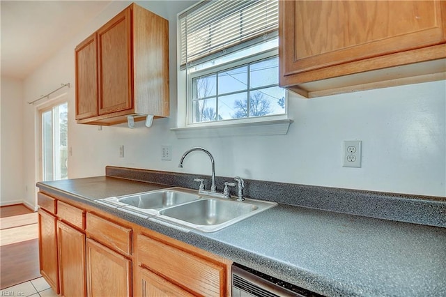 kitchen with a sink, brown cabinets, dark countertops, and dishwasher