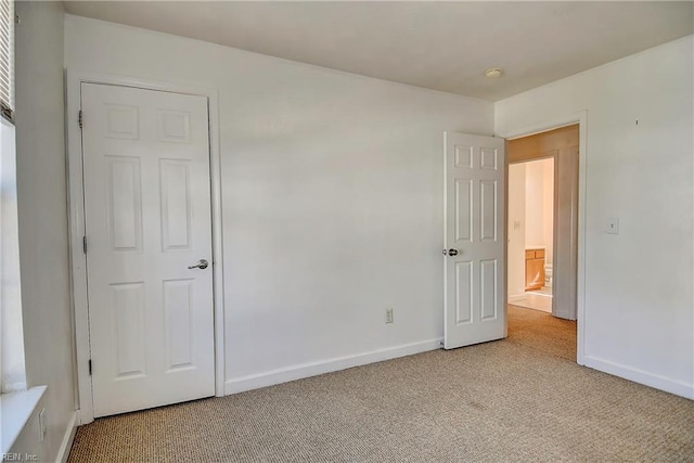 unfurnished bedroom featuring light colored carpet and baseboards