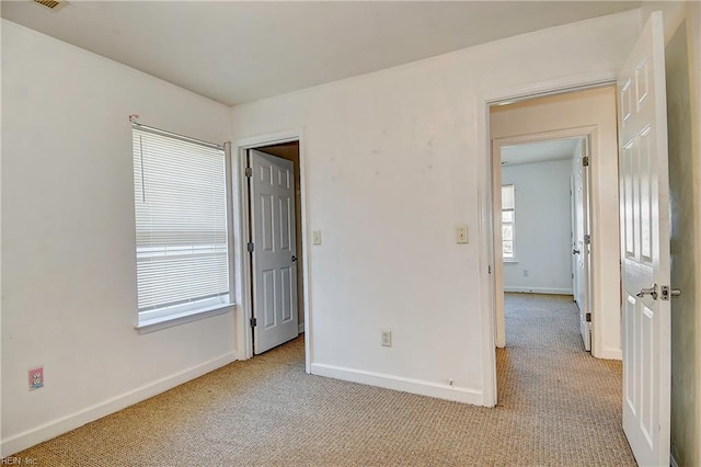 unfurnished bedroom with visible vents, light colored carpet, and baseboards