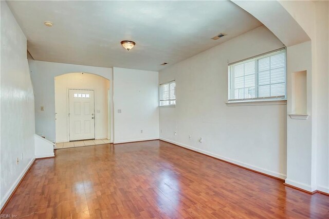 entrance foyer with visible vents, arched walkways, baseboards, and wood finished floors