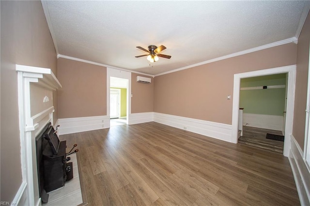 unfurnished living room featuring a fireplace, a ceiling fan, a wall mounted air conditioner, and wainscoting