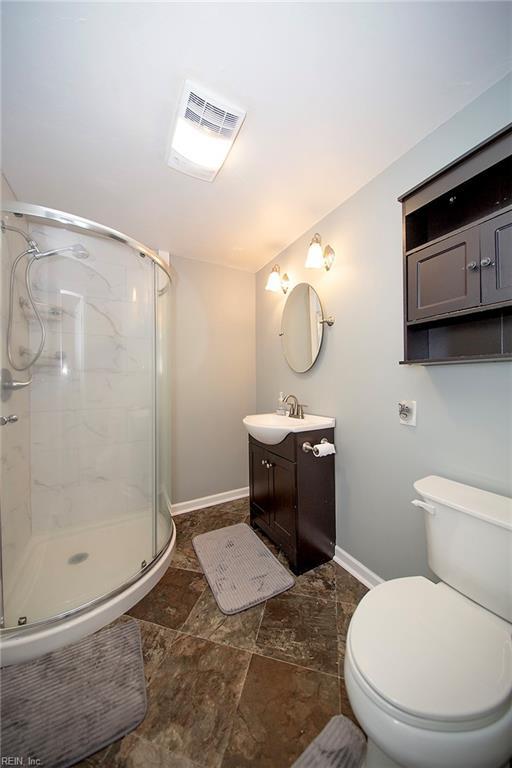 bathroom with vanity, toilet, baseboards, and a stall shower