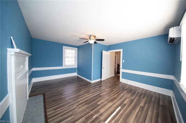 interior space featuring baseboards, an AC wall unit, a ceiling fan, and wood finished floors