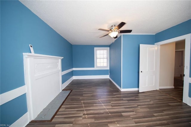 additional living space featuring baseboards, a textured ceiling, dark wood-type flooring, and ceiling fan