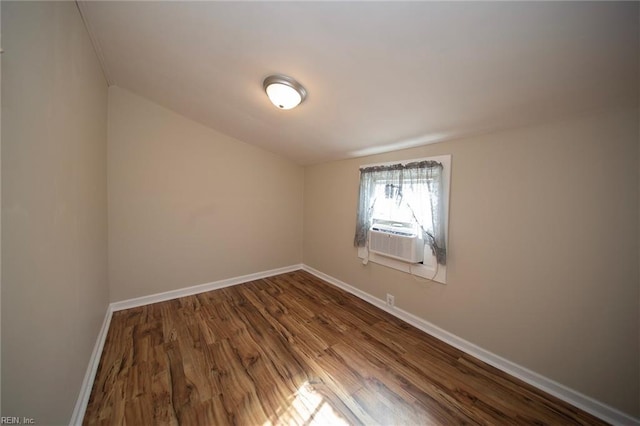 unfurnished room with dark wood finished floors, cooling unit, and baseboards