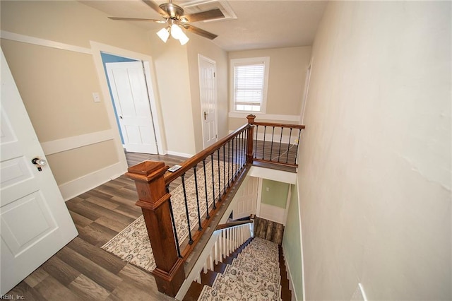 stairway featuring wood finished floors, baseboards, and ceiling fan