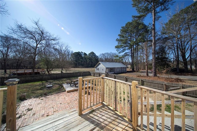 wooden terrace with an outbuilding, a fenced backyard, and a patio