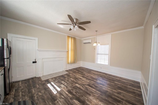 spare room featuring dark wood finished floors, a wall mounted air conditioner, ornamental molding, ceiling fan with notable chandelier, and a textured ceiling