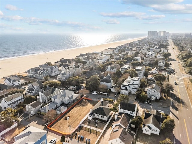 drone / aerial view featuring a view of the beach, a water view, and a residential view