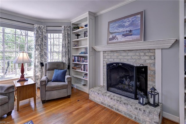 living area with a brick fireplace, light wood-style floors, and ornamental molding