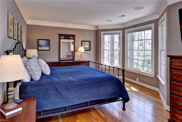 bedroom featuring visible vents, wood finished floors, baseboards, and ornamental molding