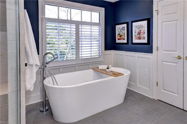 full bath with tile patterned floors, a wainscoted wall, a decorative wall, and a freestanding tub