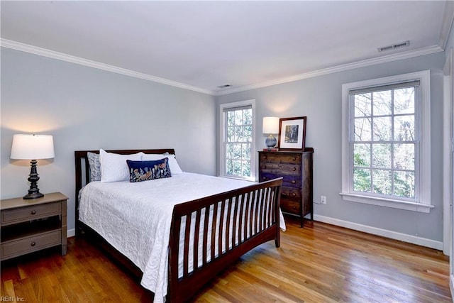 bedroom with baseboards, wood finished floors, and crown molding