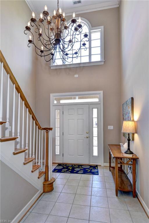 entryway featuring a wealth of natural light, stairway, a notable chandelier, and a towering ceiling