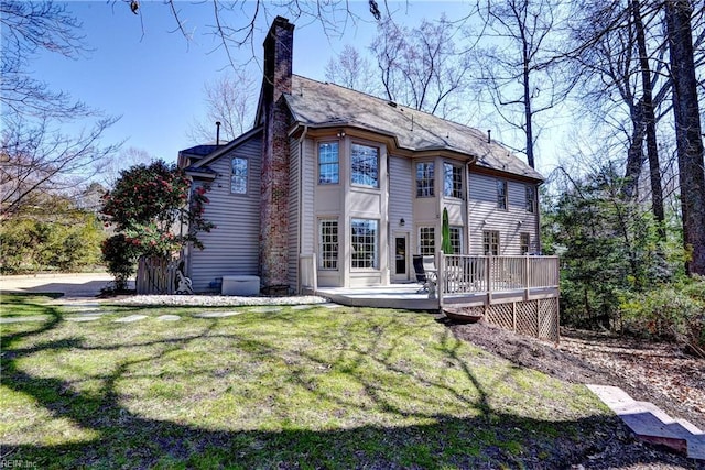 back of house with a wooden deck, a lawn, and a chimney