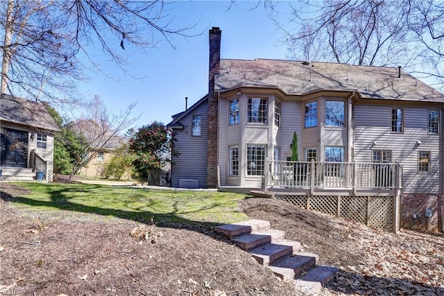 back of house featuring a wooden deck, a chimney, and a yard