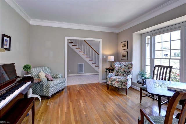 living area with wood finished floors, visible vents, and ornamental molding