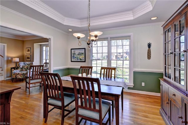 dining area with a tray ceiling, a healthy amount of sunlight, and light wood finished floors