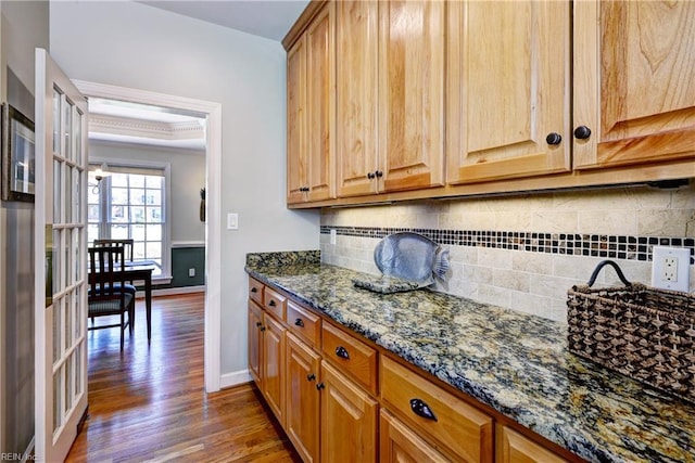 kitchen featuring dark stone counters, baseboards, tasteful backsplash, and wood finished floors