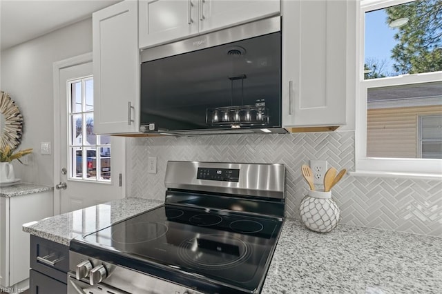 kitchen featuring tasteful backsplash, stainless steel range with electric cooktop, white cabinetry, and light stone counters