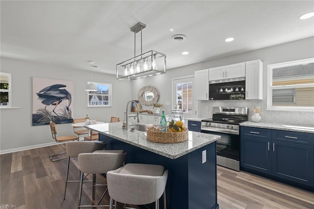 kitchen with blue cabinets, a breakfast bar, a sink, tasteful backsplash, and stainless steel range with electric cooktop