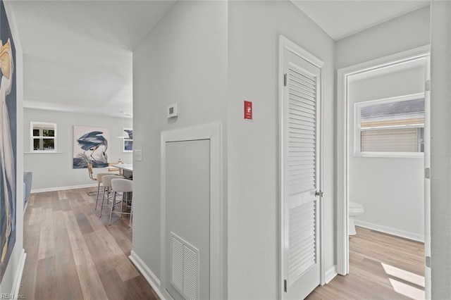 hallway featuring visible vents, baseboards, and wood finished floors