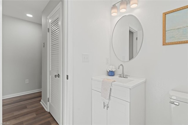 bathroom with baseboards, toilet, recessed lighting, wood finished floors, and vanity