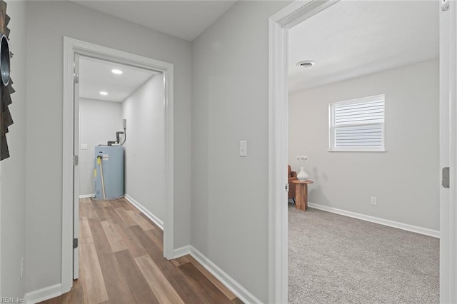 hall featuring visible vents, electric water heater, baseboards, recessed lighting, and wood finished floors