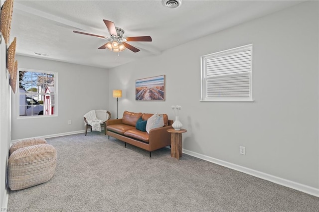 living area featuring baseboards, visible vents, carpet floors, and ceiling fan