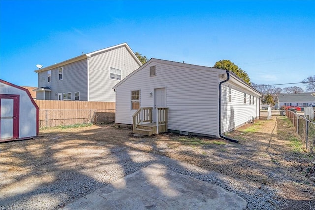 rear view of property with an outbuilding, a storage unit, and a fenced backyard