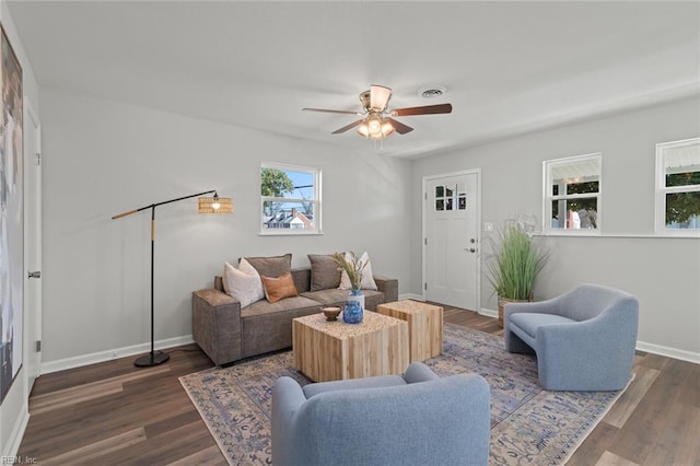 living area featuring ceiling fan, visible vents, baseboards, and wood finished floors