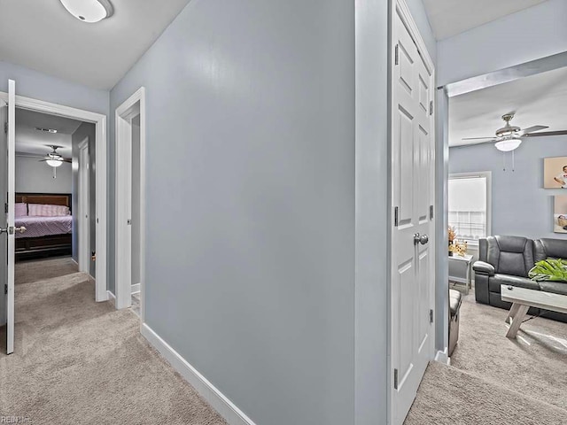 hall featuring baseboards and light colored carpet