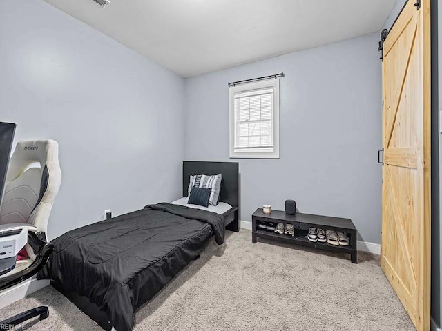 bedroom featuring a barn door, carpet flooring, and baseboards