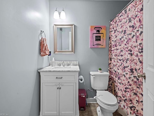 full bath featuring toilet, vanity, and baseboards