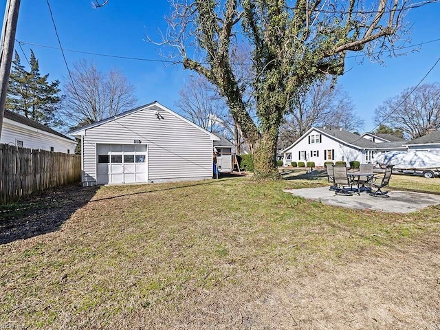 view of yard featuring an outbuilding, driveway, a detached garage, fence, and a patio area