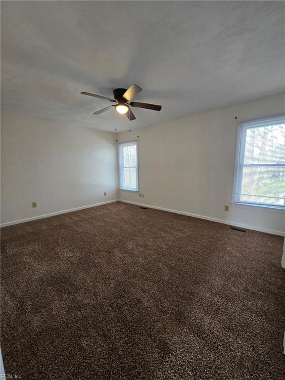 carpeted spare room featuring visible vents, ceiling fan, and baseboards