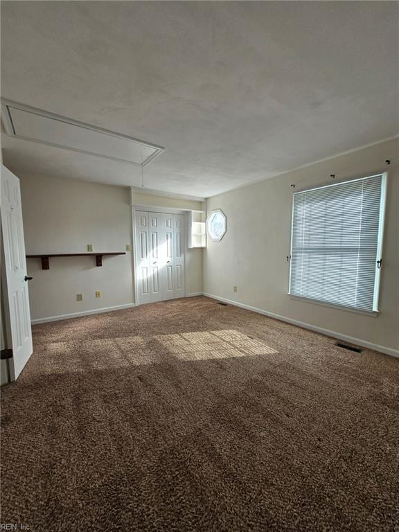 carpeted empty room featuring attic access, baseboards, and visible vents