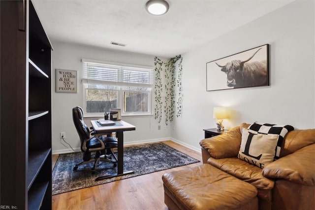 office area featuring visible vents, baseboards, and wood finished floors