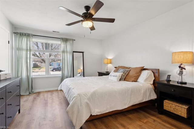 bedroom with visible vents, a ceiling fan, light wood-type flooring, and baseboards