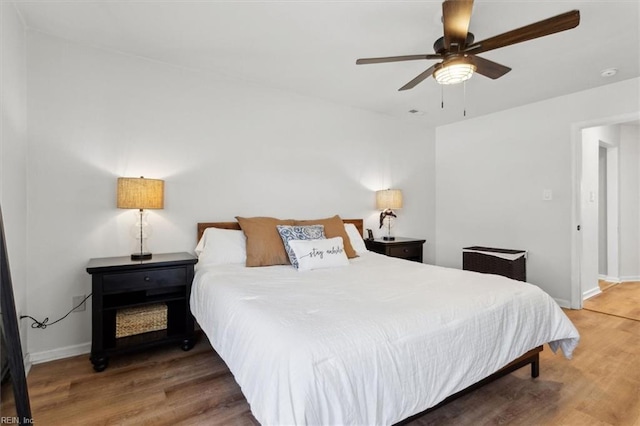 bedroom featuring ceiling fan, baseboards, and wood finished floors