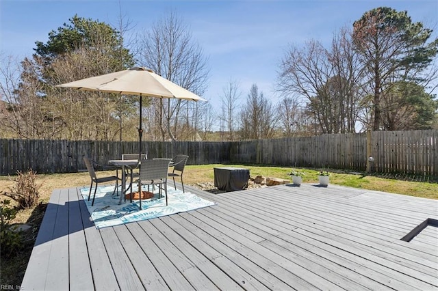 wooden terrace with outdoor dining area, a yard, and a fenced backyard