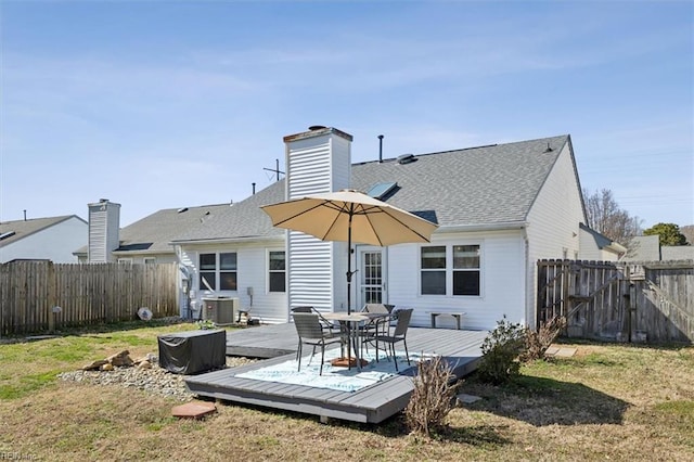 back of house with central AC, roof with shingles, a lawn, a deck, and a fenced backyard