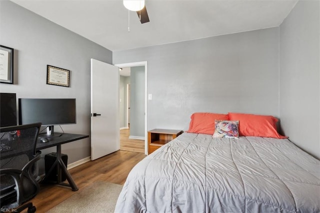 bedroom featuring baseboards, wood finished floors, and a ceiling fan