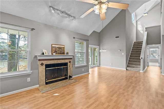 living room with a tile fireplace, stairs, baseboards, and wood finished floors