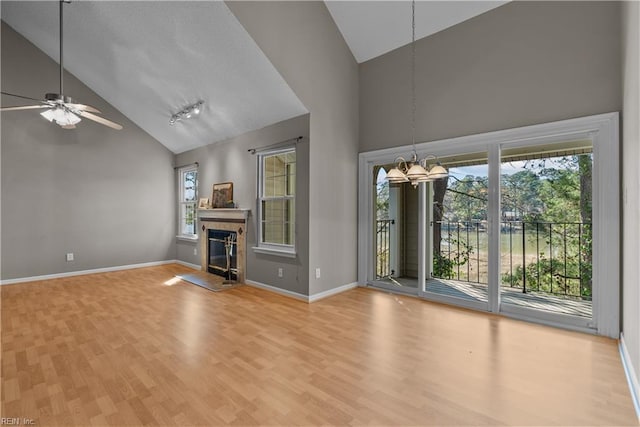 unfurnished living room featuring high vaulted ceiling, wood finished floors, baseboards, and a tile fireplace