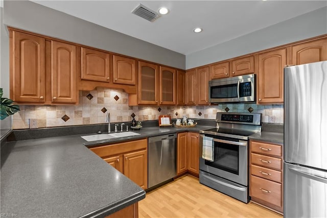 kitchen with a sink, stainless steel appliances, dark countertops, and visible vents