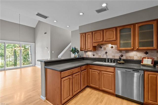 kitchen featuring dark countertops, visible vents, dishwasher, brown cabinets, and a sink